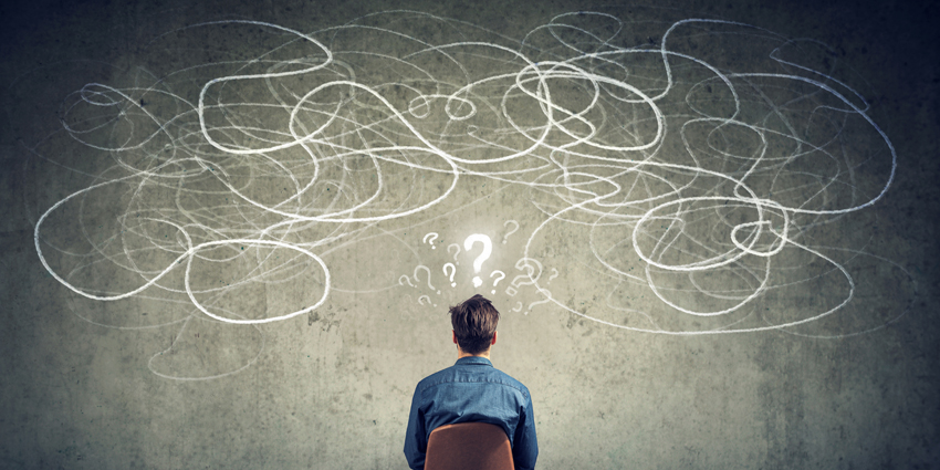 businessman sitting on chair looking at a scribble on a wall feeling confused