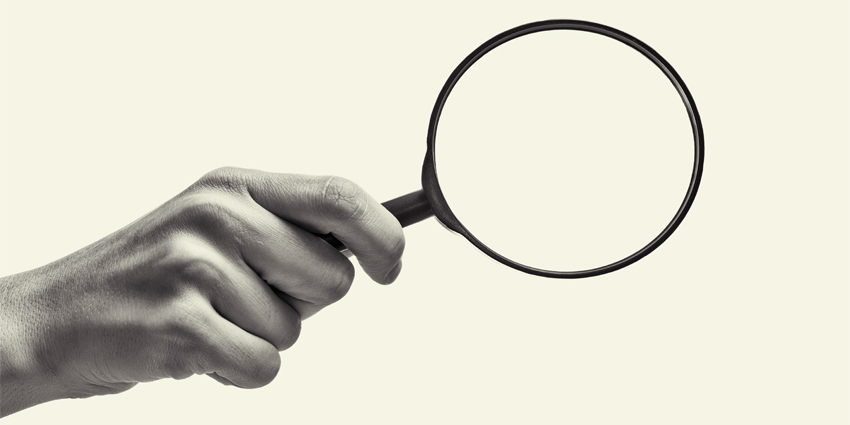 Female hand holding the magnifying glass on isolated background. Black and white image.