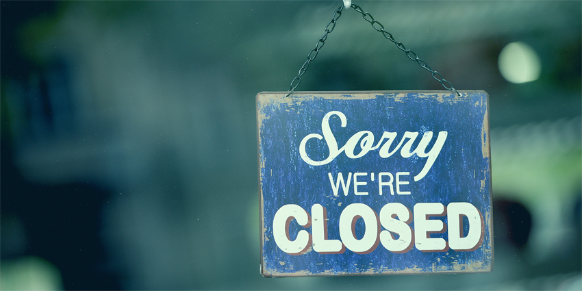 Blue closed sign in the window of a shop displaying the message 