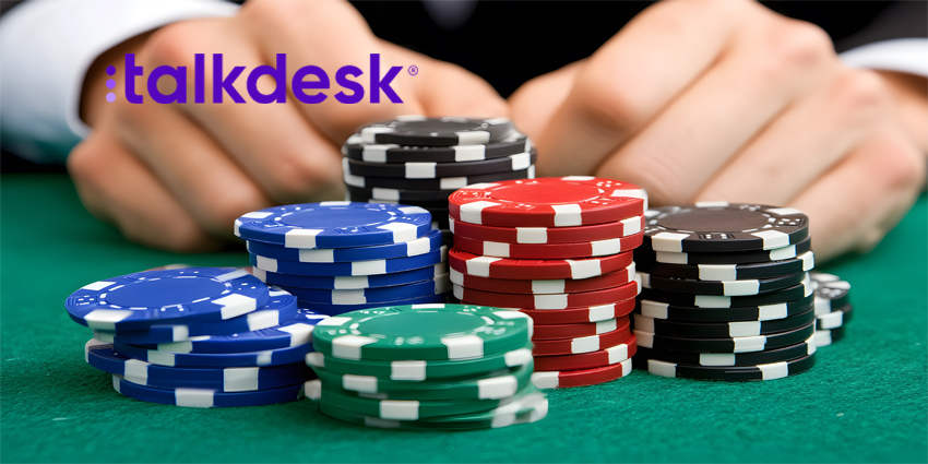 A close-up of stacks of poker chips on a green felt table, with a player's hands in the background.