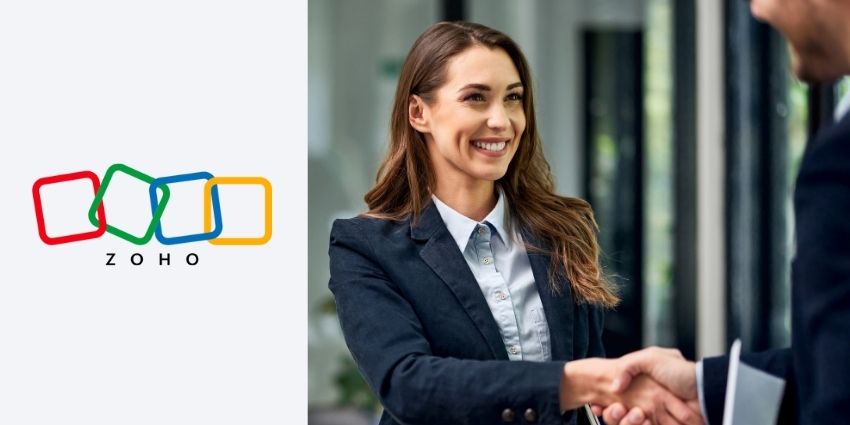 female at a job interview shaking a mans hand with the zoho logo to the left.
